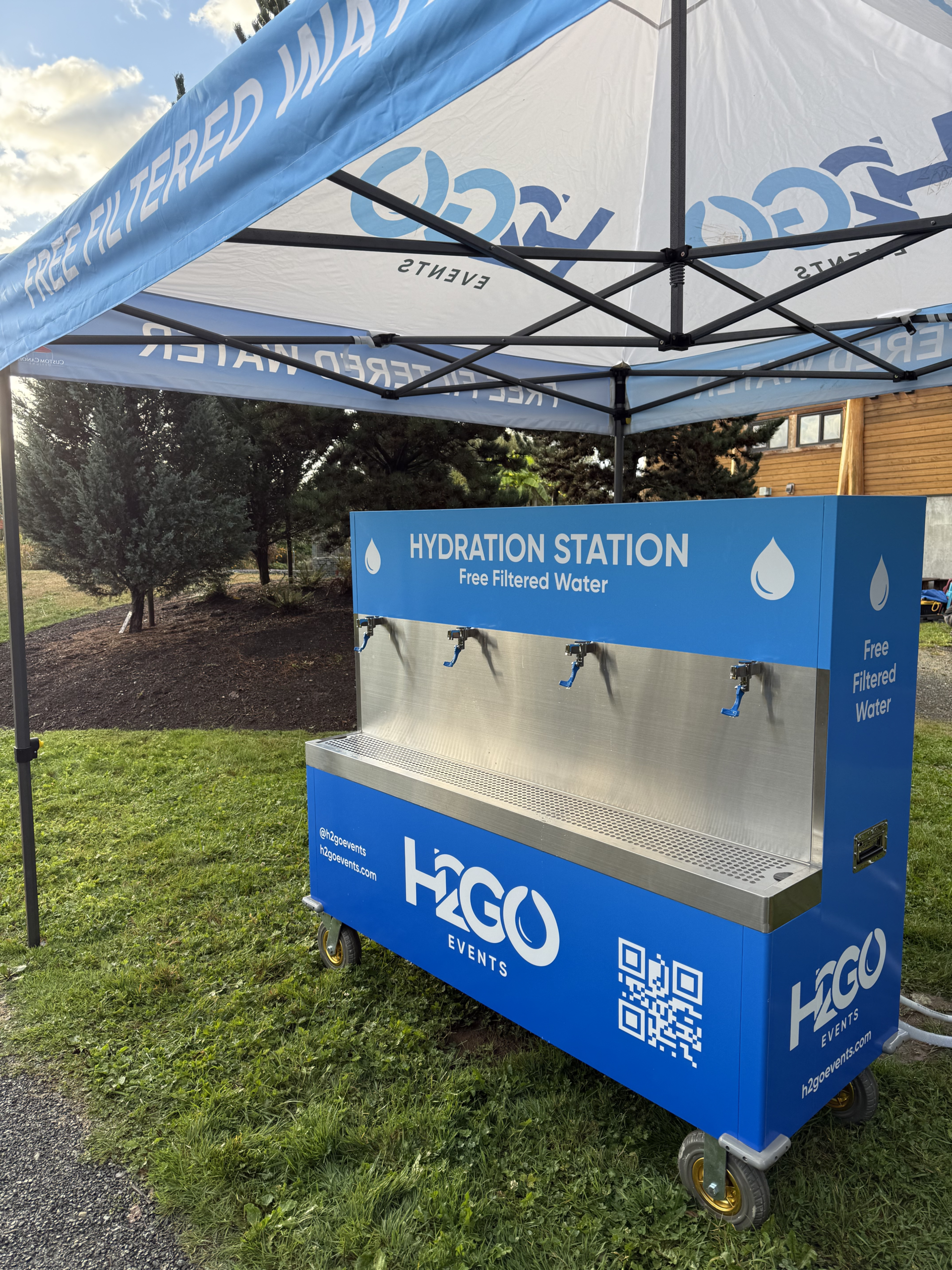 H2GO branded water refill station beneath a blue event canopy
